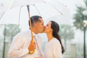 close Noivos se beijando, no templo de Fortaleza, sob muita chuva. Noivo segurando guarda chuva branco