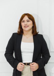 Executiva branca de cabelos ruivos com terno escuro e camisa clara. fundo branco