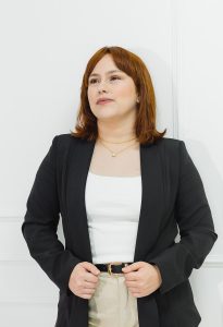 Executiva branca de cabelos ruivos com terno escuro e camisa clara. fundo branco